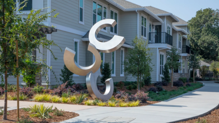 A large statue surrounded by landscaping in a commercial multi family property.
